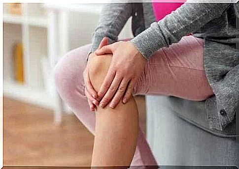 A woman holding her knee with both hands.