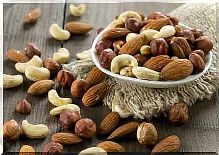 Various nuts strewn across a table and in a bowl.