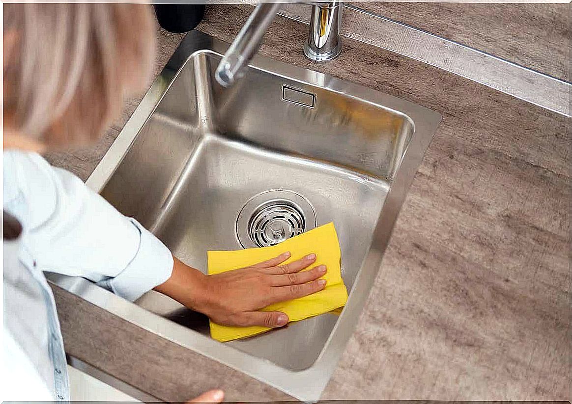 A woman cleaning a kitchen sink.