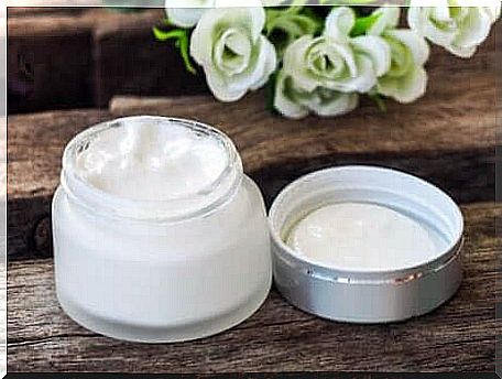 Skin cream in a jar with white roses in the background.