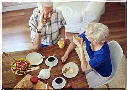 An elderly couple talking over breakfast