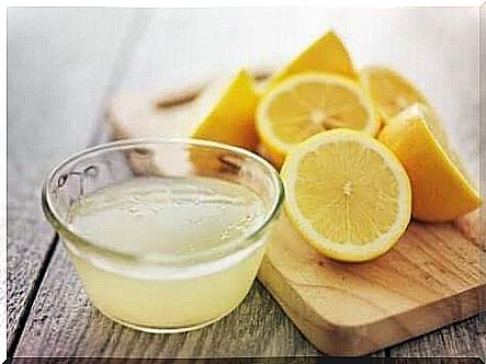 Lemon juice in a bowl with lemons lying in the background